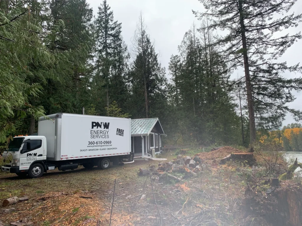  PNW Construction & Energy Services truck parked near a cabin in the forest, providing free home energy efficiency estimates in Washington’s Skagit and Snohomish counties.